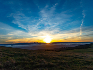 The sun rises over a foggy valley full of trees