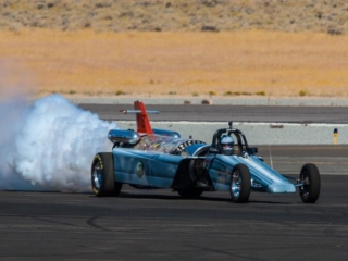 A jet-powered dragster drives across the tarmac