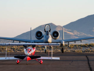 A jet taxies towards a small biplane.