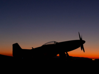 An airplane sits parked at early sunrise.