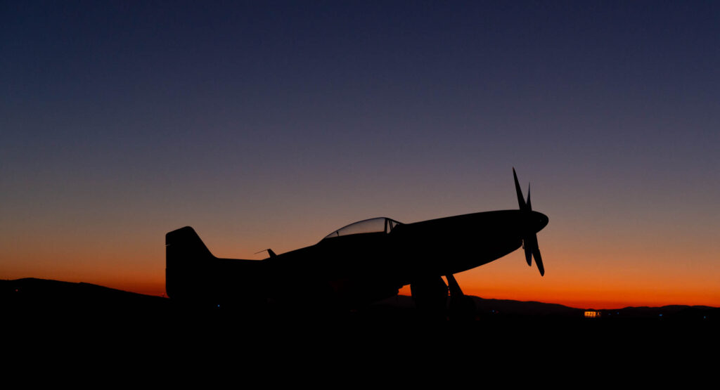 An airplane sits parked at early sunrise.