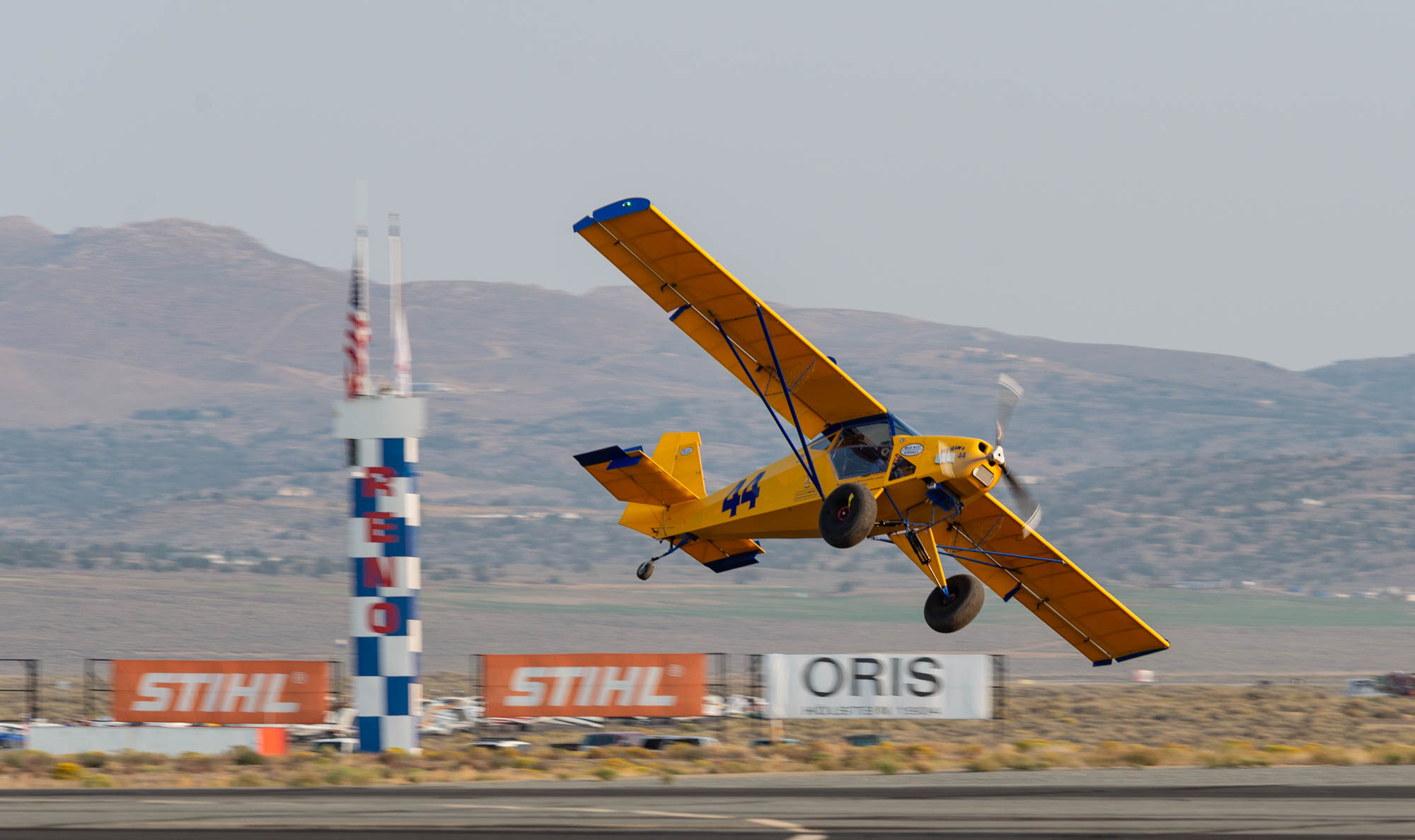 A STOL race plane flies past the home pylon, flying at a dramatic angle.