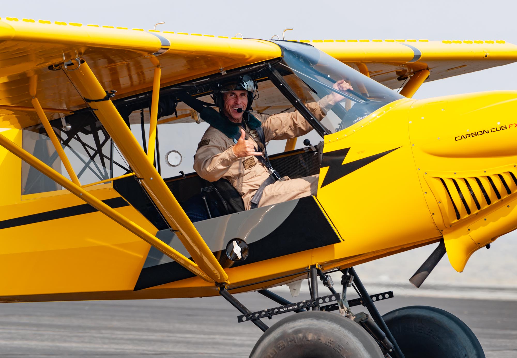 A smiling man taxis by in an airplane and gives a shaka sign