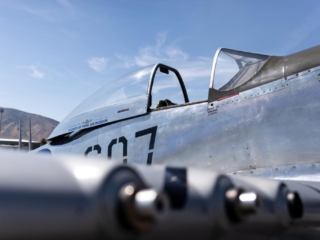 A low photo of an airplane, looking across the wing guns and up at the cockpit.