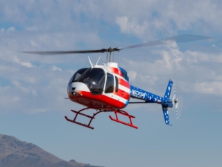 A helicopter with an American Flag paint job hovers low overhead
