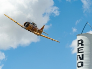 An airplane flies overhead past a racing pylon