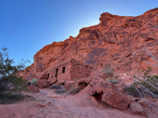A view of a rocky cliff with a stone house at the base