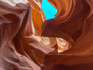 A view looking up through a desert canyon, with a little bit of sky in the background