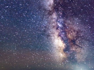 The milky way comes down the sky over a fence and fog