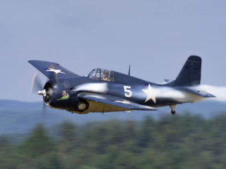 An airplane flies past the camera, with performer smoke coming from the engine